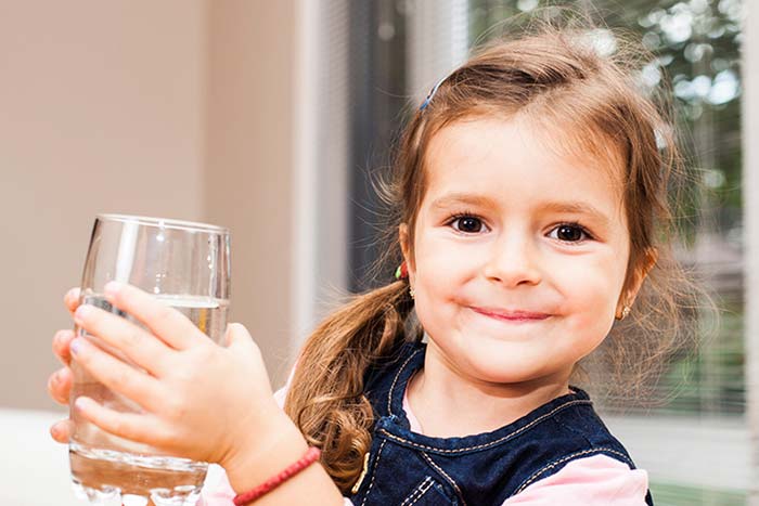 A small girl holding a glass of water