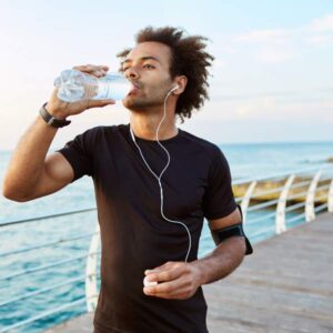 man drinking water while jogging